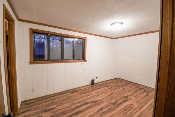 a view of empty room with wooden floor and fan