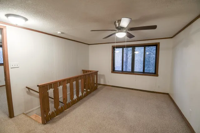 an empty room with windows and fan