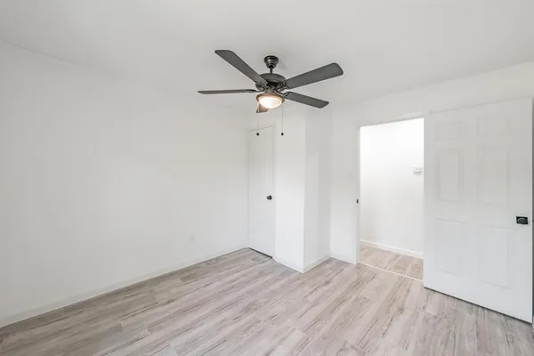 an empty room with wooden floor and a ceiling fan
