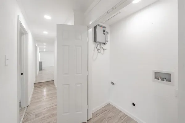 a view of a hallway with wooden floor and a bathroom