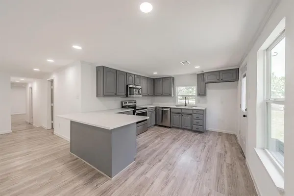 a kitchen with stainless steel appliances a sink wooden floor and window
