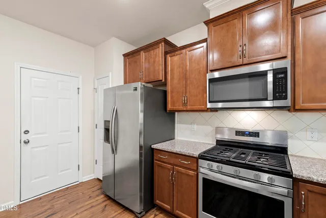 a kitchen with stainless steel appliances granite countertop a stove microwave and refrigerator