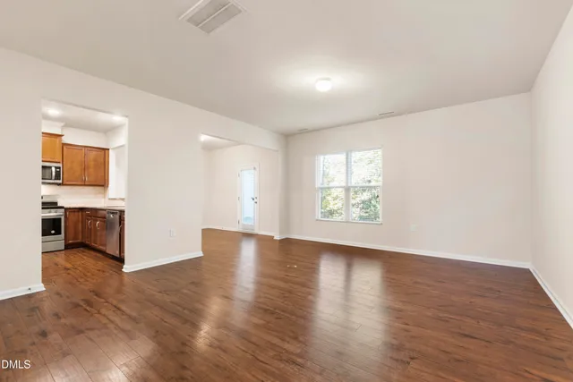 a view of an empty room with window and wooden floor