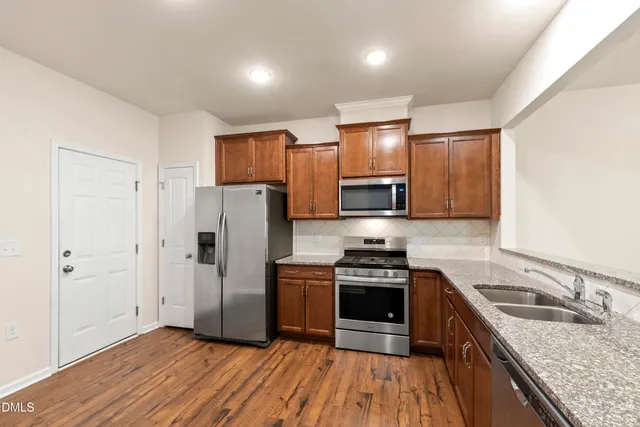 a kitchen with granite countertop a stove top oven and refrigerator