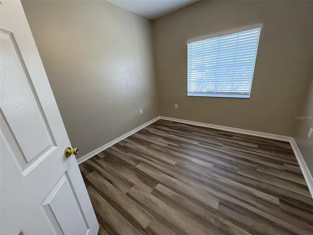 an empty room with wooden floor and a window