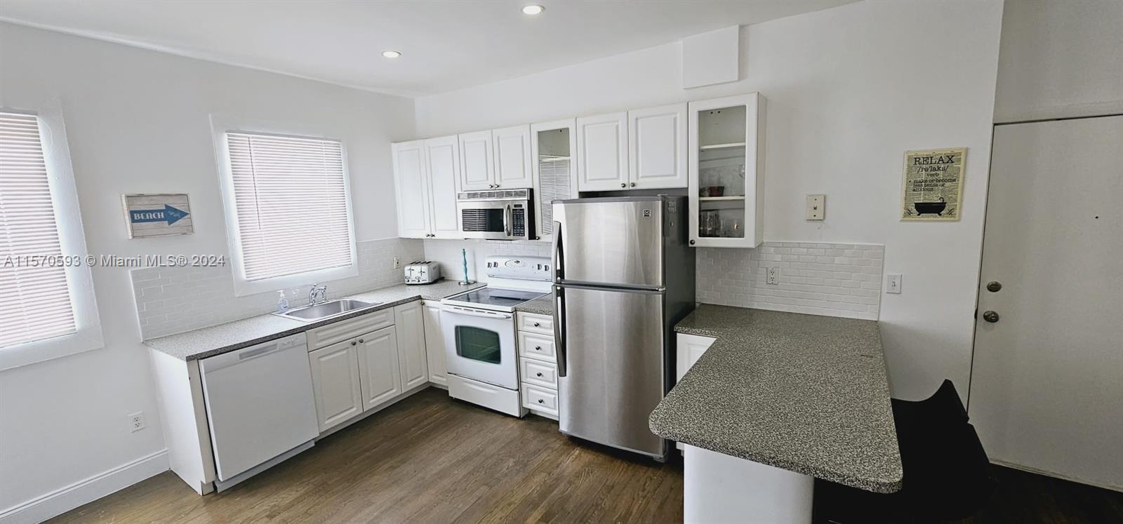 a kitchen with stainless steel appliances granite countertop a refrigerator a stove a sink and white cabinets