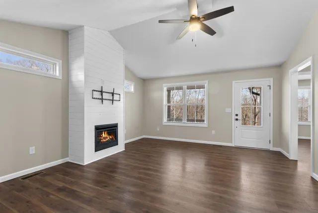 a view of a livingroom with wooden floor a fireplace and a window