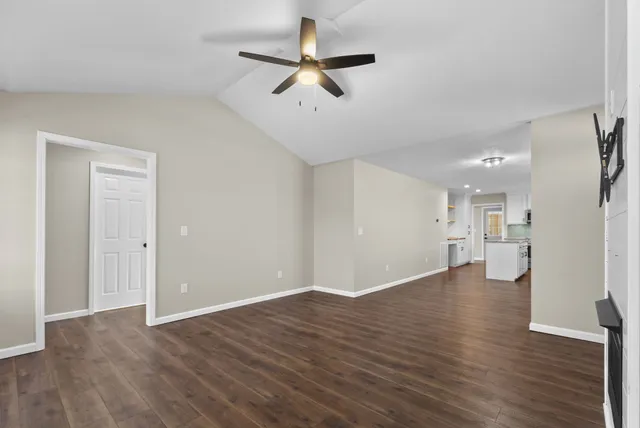 a view of an empty room with a window and wooden floor