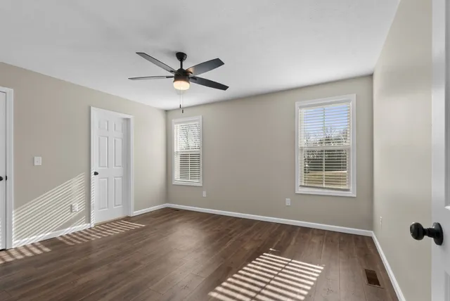 a view of an empty room with a window and wooden floor