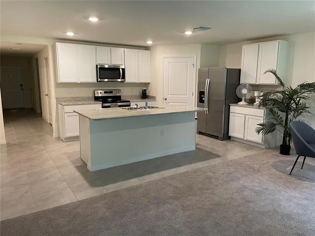 a kitchen with stainless steel appliances granite countertop a stove top oven a sink and a refrigerator