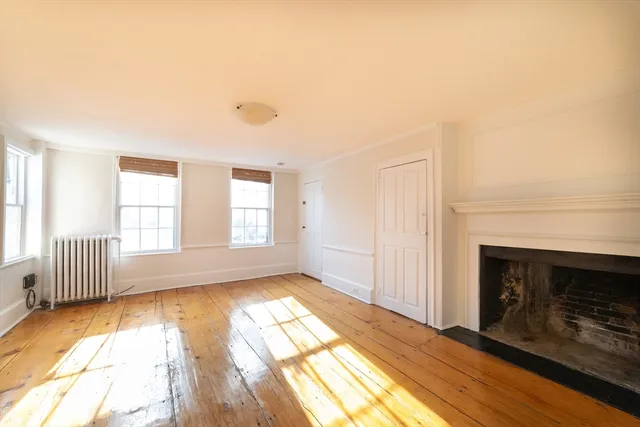 a view of empty room with wooden floor and fireplace