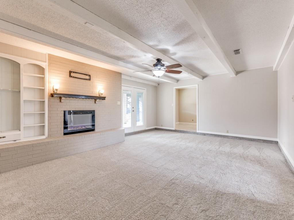 7325 Reed Road Azle, TX 76020 - Photo 13 of 38 Unfurnished living room with a textured ceiling, carpet, built in features, a fireplace, and a ceiling fan