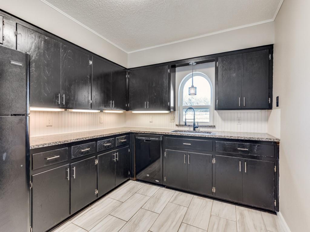 7325 Reed Road Azle, TX 76020 - Photo 19 of 38 Kitchen featuring dark cabinetry, black appliances, a textured ceiling, light stone counters, and crown molding