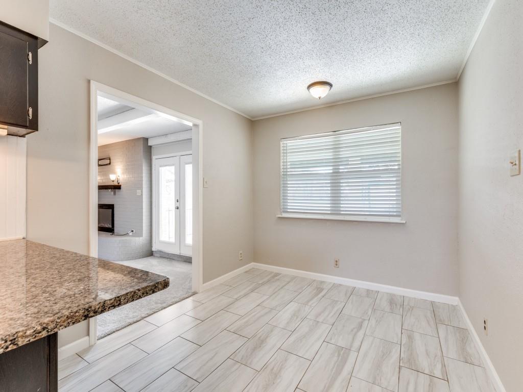 7325 Reed Road Azle, TX 76020 - Photo 21 of 38 Unfurnished dining area with a textured ceiling, a fireplace, and crown molding