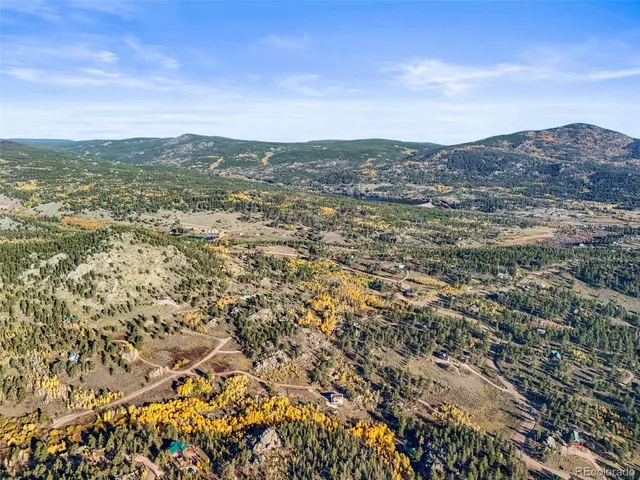 an aerial view of residential houses with outdoor space and trees