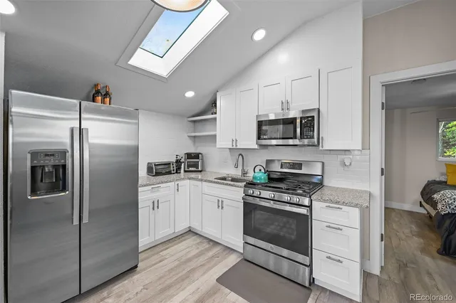 a kitchen with white cabinets stainless steel appliances and a counter top space