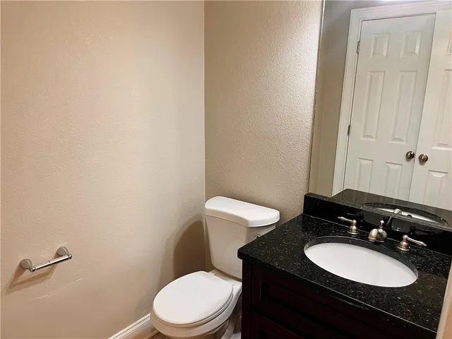 a bathroom with a granite countertop toilet and sink