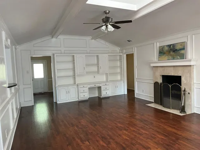 a view of a livingroom with a fireplace a ceiling fan and windows