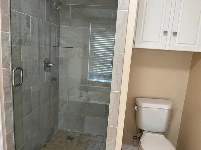 a bathroom with a granite countertop sink a toilet and a shower