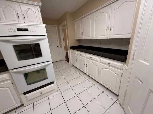 a kitchen with white cabinets and sink