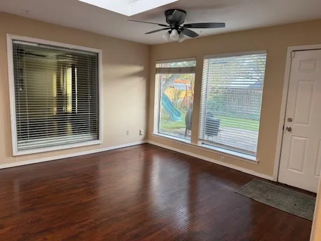 an empty room with wooden floor and windows