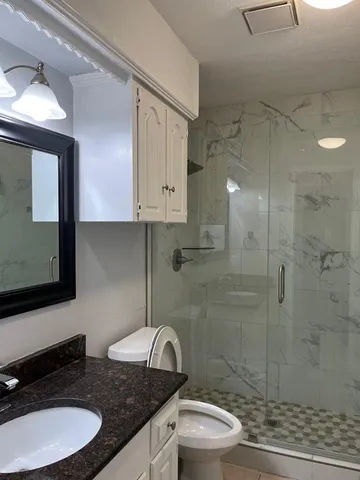 a bathroom with a granite countertop toilet sink and mirror