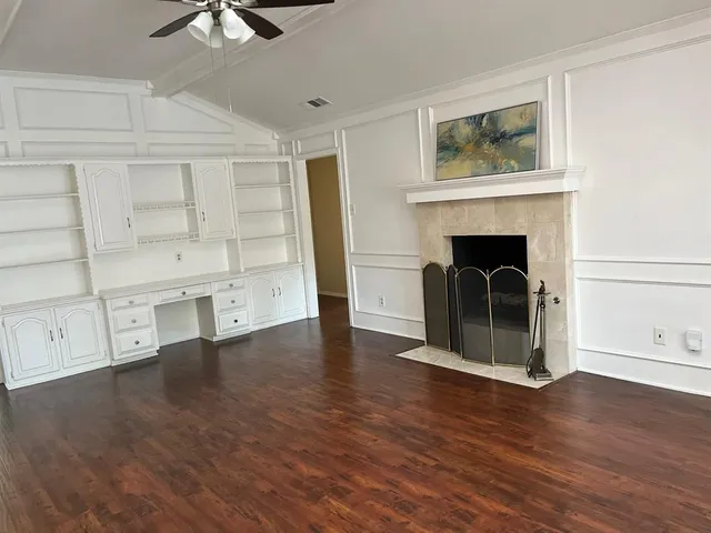 an empty room with wooden floor fireplace and windows