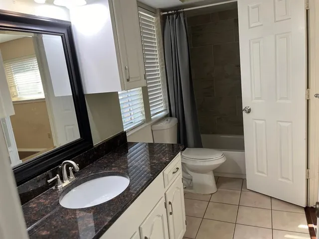 a bathroom with a granite countertop sink toilet a mirror and shower