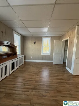 a view of kitchen and empty room with wooden floor