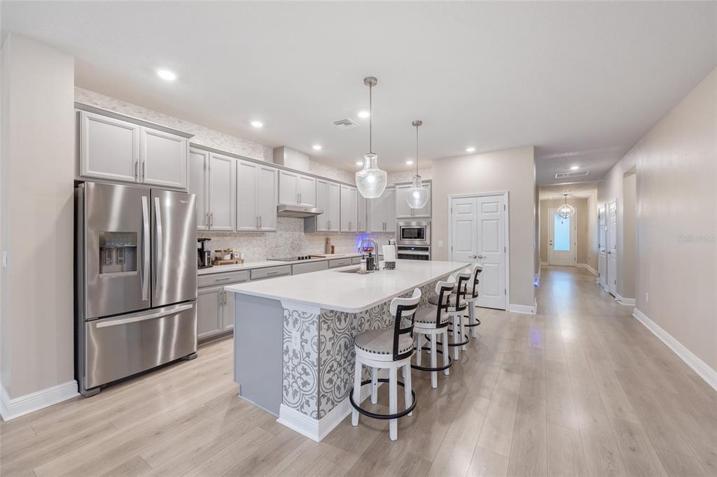 11720 Chevelon Lane Parrish, FL 34219 - Photo 8 of 70 a kitchen with stainless steel appliances kitchen island granite countertop a refrigerator a stove a sink and a dining table with wooden floor