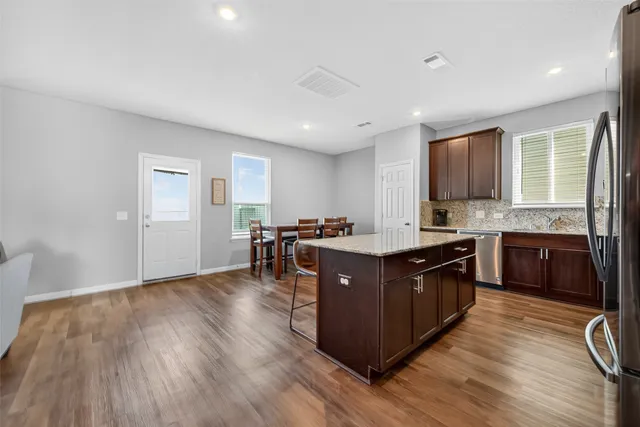 a kitchen with stainless steel appliances granite countertop a stove a sink dishwasher a refrigerator and a oven with wooden floors