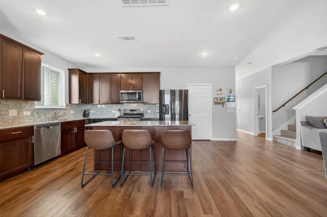 a kitchen with stainless steel appliances granite countertop wooden floors a stove and a refrigerator