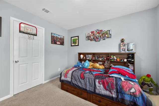 a bedroom with a bed painting on the wall and dresser