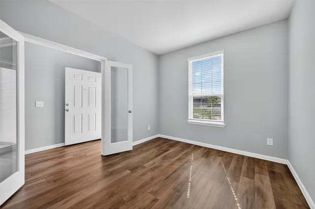 a view of an empty room with wooden floor and a window