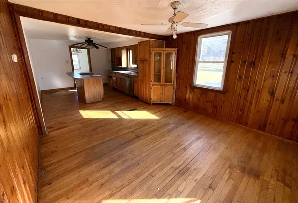 a view of empty room with wooden floor and fan