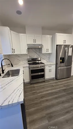 a kitchen with granite countertop a sink stove and refrigerator