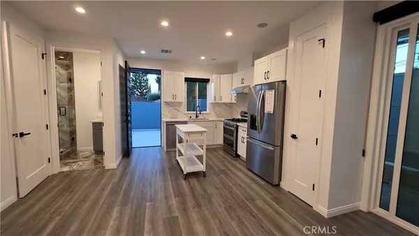 a kitchen with stainless steel appliances a refrigerator and wooden floor
