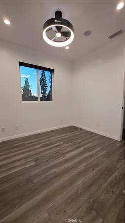 a view of an empty room with a dishwasher and wooden floor