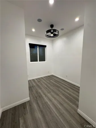 a view of an empty room with a ceiling fan and wooden floor