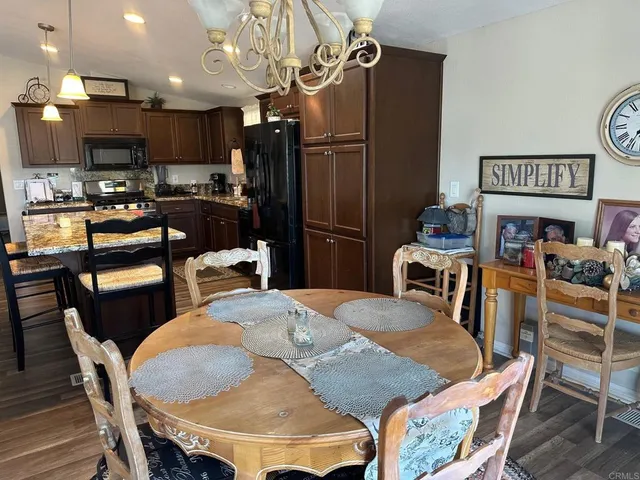 a kitchen with stainless steel appliances kitchen island granite countertop a dining table chairs refrigerator and a sink