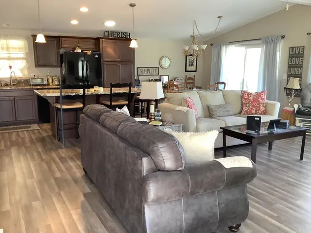 a living room with couches and kitchen view with wooden floor