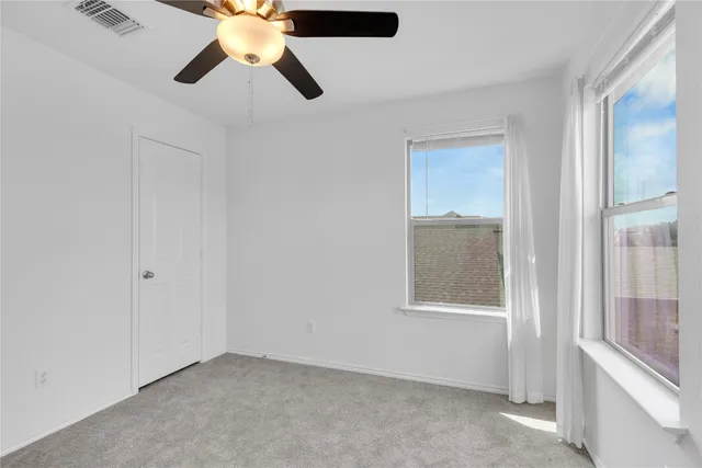 an empty room with windows and fan