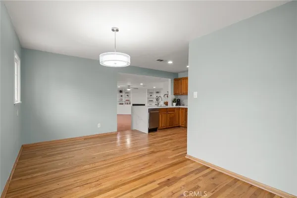 a view of kitchen and empty room with wooden floor