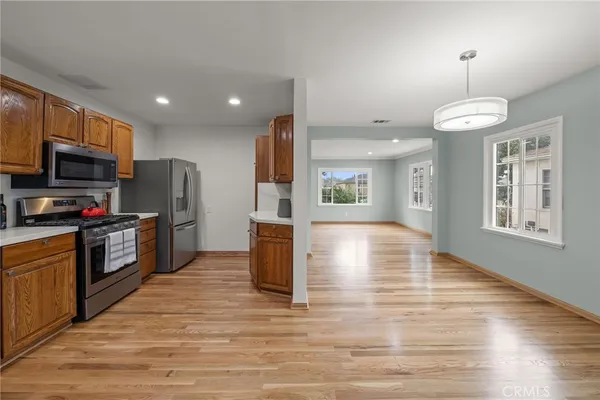 a kitchen with stainless steel appliances kitchen island granite countertop a refrigerator a stove top oven a sink dishwasher and a refrigerator with wooden floor
