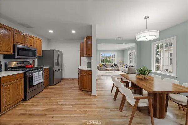 a kitchen with stainless steel appliances kitchen island granite countertop a refrigerator a stove top oven a sink dishwasher and white cabinets with wooden floor