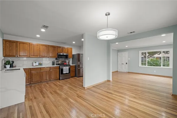 an open kitchen with wooden floor and stainless steel appliances