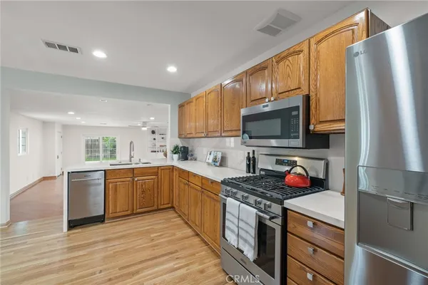 a kitchen with stainless steel appliances granite countertop a refrigerator a stove top oven a sink dishwasher and wooden cabinets with wooden floor