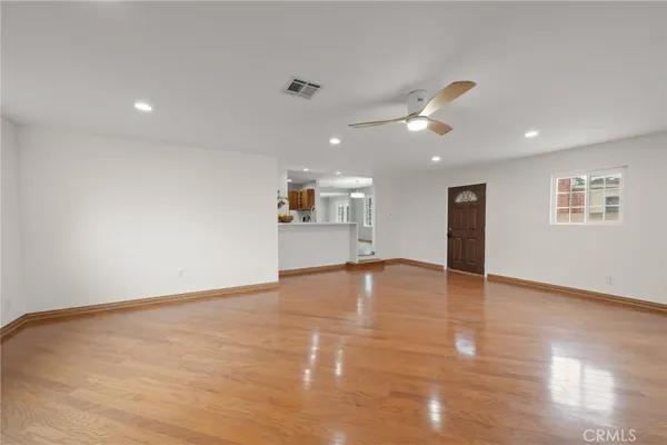 a view of empty room with wooden floor and ceiling fan