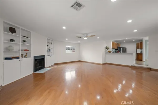 a view of a big room with wooden floor and a kitchen