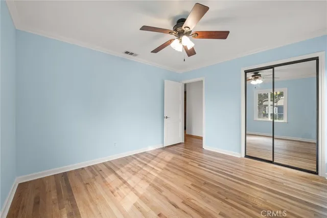 wooden floor in an empty room with a chandelier fan